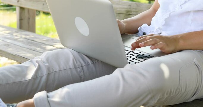 Young woman enjoys writing with her laptop outdoors