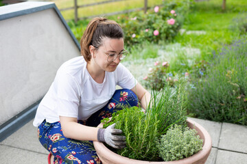 A young girl in a white T-shirt plant a tree in pot at home. Growing seedlings at home. Delicious and healthy food for salad at home.A woman is planting a herb garden in a pot