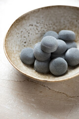 Bowl with korean traditional mochi or chapssaltteok, vertical shot on a beige stone background, close-up, selective focus