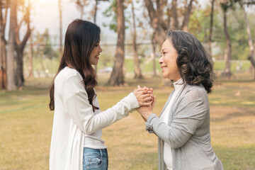 Close-up of granddaughter consoling her senior grandmother and touching hand when in park