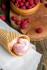 Waffle cone with white pink cream ice cream and raspberries