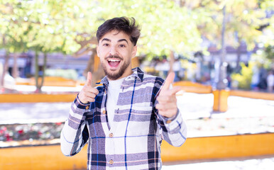 Obraz premium young handsome man feeling happy, cool, satisfied, relaxed and successful, pointing at camera, choosing you