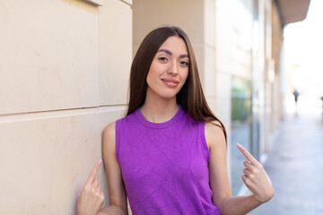 young pretty woman looking proud, arrogant, happy, surprised and satisfied, pointing to self, feeling like a winner