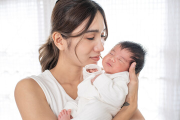 happy loving family. mother playing with her baby hugging in the bedroom , portrait of asian mother playing with newborn baby, health care family love together. asian girl lifestyle..