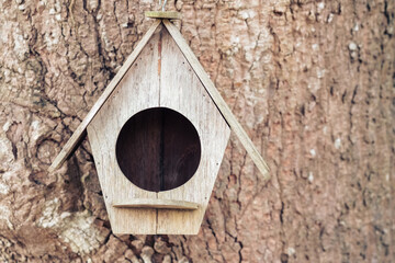 Old wooden bird house hanged on the tree trunk