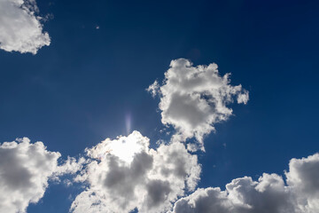 Naklejka na ściany i meble Illuminated by sunlight blue sky with clouds and sun