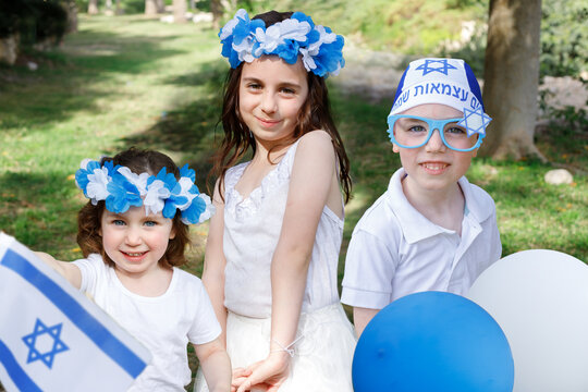Children with attributes  of the Israeli holiday Independence Day. White-blue balloons, Israeli flag.