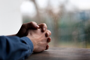 Young mam praying from window. religion concept.