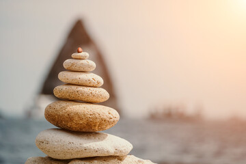 Fototapeta na wymiar Balanced rock pyramid on sea pebbles beach, sunny day and clear sky at sunset. Golden sea bokeh on background. Selective focus, zen stones on sea beach, meditation, spa, harmony, calm, balance concept