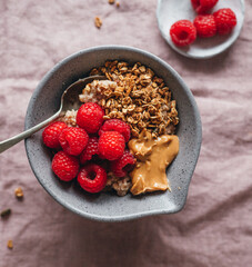 Bowl of porridge oats topped with raspberries and granola