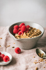 Breakfast bowl set on a table with fresh raspberries