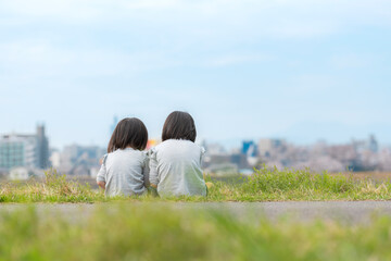 Naklejka premium 春の河川敷で遊ぶ幼い姉妹