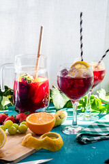 Sangria or tinto de verano, a refreshing drink typical of Spain with red wine, lemon, ice and fruits, vertical photograph of glass cups, with fruits on the table and copy space.