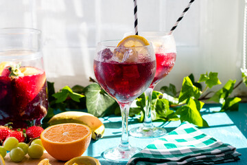 Sangria or tinto de verano, a refreshing drink typical of Spain with red wine, lemon, ice and fruit, horizontal photograph of glass cups, with fruit on the table and copy space.