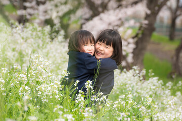 幼稚園の制服を着た姉妹と満開の桜