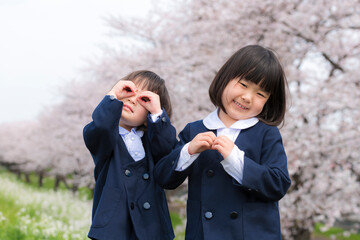 幼稚園の制服を着た姉妹と満開の桜