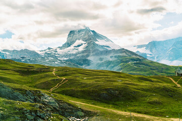 Fototapeta premium View of Matterhorn peak covered with clouds in summer with meadow green fields, Zermatt, Switzerland