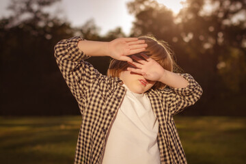 Photophobia Light Sensitivity content. Boy covering eyes by hand from sunlight outdoors. Sun Damage...