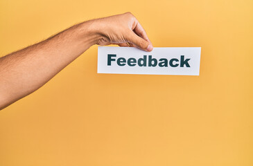 Hand of caucasian man holding paper with feedback word over isolated white background