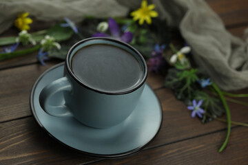 brown wooden background with spring flowers, leaves and coffee