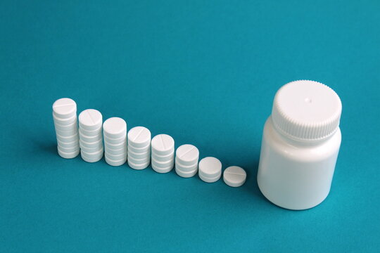 On a turquoise background, round medicine pills stand in the form of a ladder.