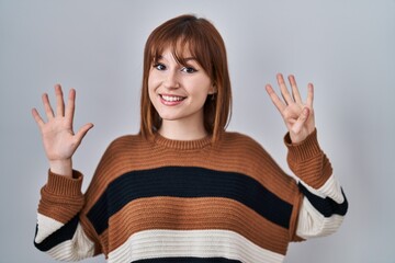 Young beautiful woman wearing striped sweater over isolated background showing and pointing up with...