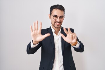 Fototapeta premium Handsome business hispanic man standing over white background showing and pointing up with fingers number eight while smiling confident and happy.