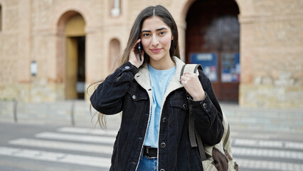 Obraz premium Young beautiful hispanic woman student smiling confident talking on smartphone at street