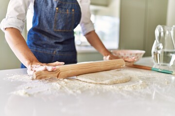 Obraz na płótnie Canvas Young blonde woman kneading pizza dough at kitchen