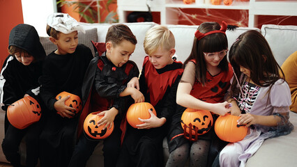 Group of kids wearing halloween costume eating candies at home