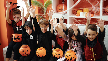 Obraz premium Group of kids wearing halloween costume with hands raised up at home