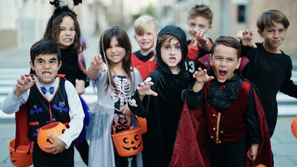 Group of kids wearing halloween costume doing scare gesture at street