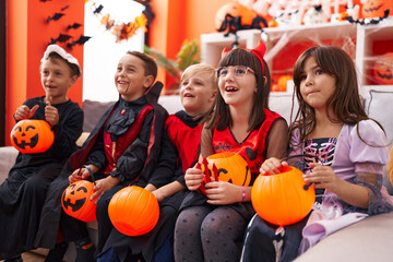 Group of kids wearing halloween costume holding pumpkin basket at home