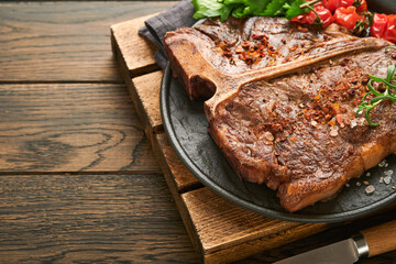 Steaks T-bone. Sliced beef grilled T-bone or porterhouse meat steak with spices rosemary and pepper on black marble board on old wooden background. Top view. Mock up.
