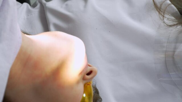 Female dentist and assistant removing dental calculus from teeth. Visit is in proffessional dental clinic. Woman sits on dental chair. Drilling and treatment of tooth, filling. vertical video