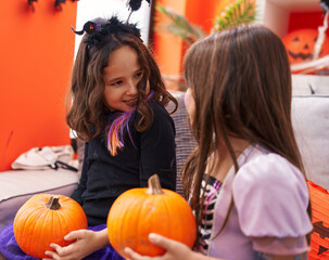 Adorable girls having halloween party holding pumpkin at home