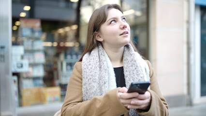 Young blonde woman smiling confident using smartphone at street