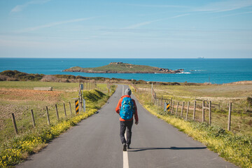 Fototapeta premium Man full of enthusiasm embarks on his journey along the Fisherman trail - Rota Vicentina along the Atlantic coast of Portugal. Adventurous backpacker hits the road in the spring months
