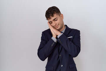 Young hispanic business man wearing suit and tie sleeping tired dreaming and posing with hands together while smiling with closed eyes.