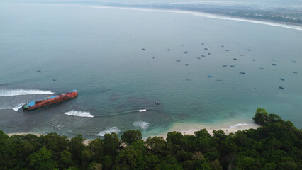 Obraz premium Abandoned ship at the sea near seashore with trees all around. Boats in the ocean aerial view, Pasir Putih, Pangandaran Indonesia