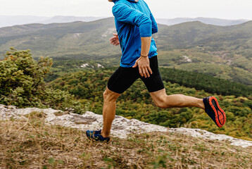 male runner in windbreaker and tights running along precipice, man jogger athlete run mountain trail © sports photos