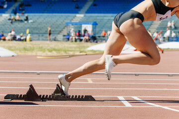 close-up female sprinter start from starting blocks run on stadium track, summer athletics...