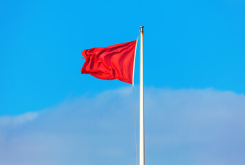 Red flag waving against blue sky 