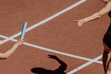 hand women runner passing baton running relay race in summer athletics championship