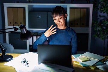 Young beautiful woman working at the office at night showing and pointing up with fingers number four while smiling confident and happy.