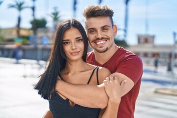 Obraz premium Man and woman couple smiling confident hugging each other at street