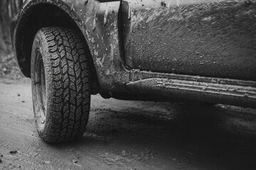 Close to the off-road tire. Protector for various surfaces, universal. Mud, stones, country road. All-wheel drive vehicle. 4x4 SUV on dirt road. Black and white