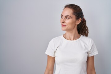 Fototapeta premium Beautiful brunette woman standing over isolated background smiling looking to the side and staring away thinking.