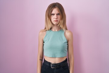 Blonde caucasian woman standing over pink background skeptic and nervous, frowning upset because of...