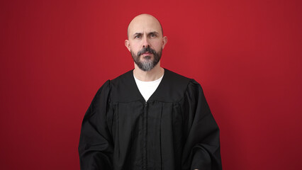 Young bald man wearing costume standing over isolated red background